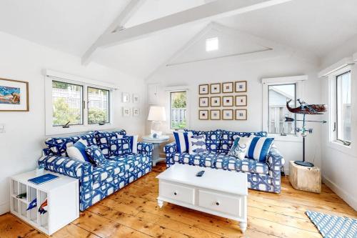 a living room with blue and white couches and a table at Oceanfront Cottage & Studio on Mill Cove w/ Water Views, Deck - Walk Downtown in Boothbay Harbor