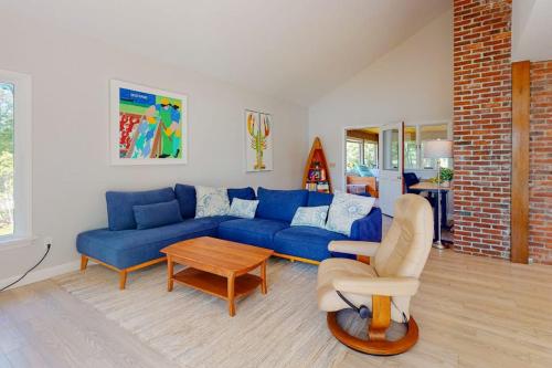a living room with a blue couch and a table at Water-view retreat with beach access, deck, grill, EV charger & lawn games in North Harpswell