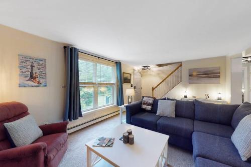 a living room with a couch and a table at Serene home with a deck, grill, firepit, board games, washer/dryer, & mtn views in East Lamoine