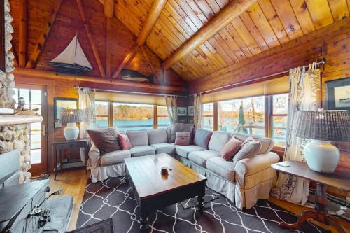 a living room with a couch and a table at Riverfront retreat with a furnished deck, washer/dryer & fast WiFi in Boothbay