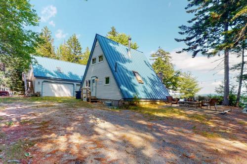 a large white barn with a blue roof at Waterfront A-frame on George's Pond with views, private dock, beach, kayaks, SUP in Franklin