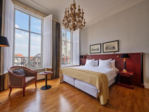 a bedroom with a large bed and a chandelier at Grand Hotel en Résidence De Draak in Bergen op Zoom
