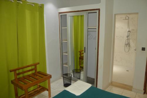 a bathroom with green curtains and a bed and a shower at OABY'S Hôtel in Bobo-Dioulasso