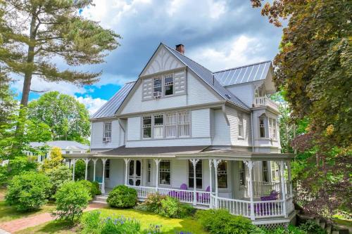 a white house with a porch and trees at Beautiful home with Ping-Pong, fast WiFi & W/D - walk to dining in Wiscasset
