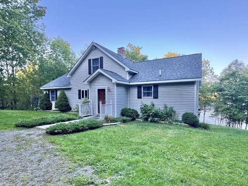 a white house with a yard at Riverfront home w/ deck, amazing views & firepit - near the best of Maine in Stockton Springs