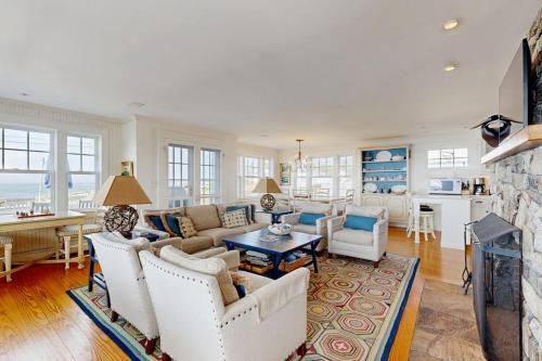 a living room with white furniture and a fireplace at Oceanfront home incredible ocean views, deck & location in Boothbay