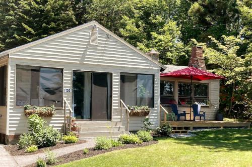 a small house with a porch and a red umbrella at Ocean-view cottage near beach with deck, grill, & full kitchen in Bristol