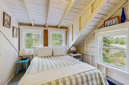 a bed in a room with two windows at Bayfront cottage with fantastic views & minutes to downtown - Dog-friendly in Boothbay Harbor