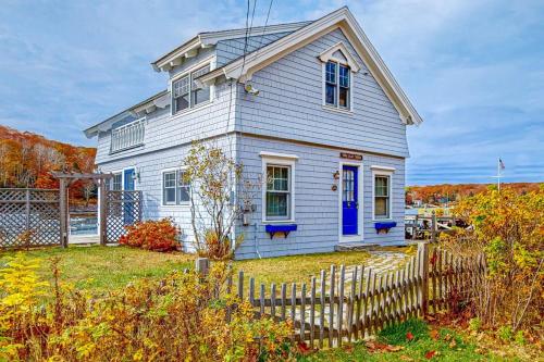 a white house with a blue door and a fence at Enchanting Oceanfront Cottage with Breathtaking Views and Modern Comforts in East Boothbay
