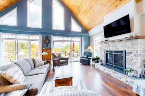 a living room with a stone fireplace and a tv at Secluded hilltop home with beautiful Cadillac Mountain view and multiple decks in Bar Harbor