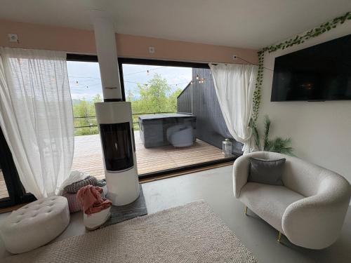 a living room with a fireplace and a chair and a porch at Sunrise View Lapland, Jacuzzi and sky view in Kilpisjärvi