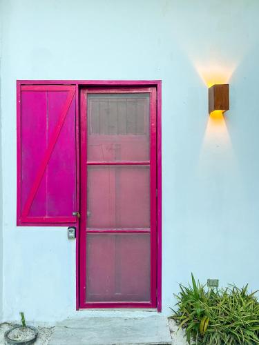 a red door on the side of a white house at Ca Nikte Cabañas in El Cuyo