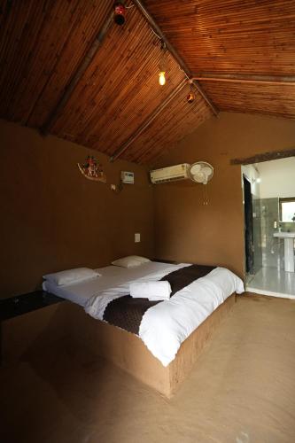 a large bed in a room with a wooden ceiling at Rupani Dhani Farmhouse by Belmore in Mandkaula