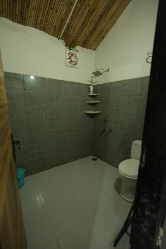 a bathroom with a toilet and a clock on the wall at Rupani Dhani Farmhouse by Belmore in Mandkaula