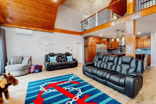 a living room with black leather furniture and a blue rug at Luxurious waterfront home with deck, firepit, hot tub, fireplace, & pool table in Boothbay