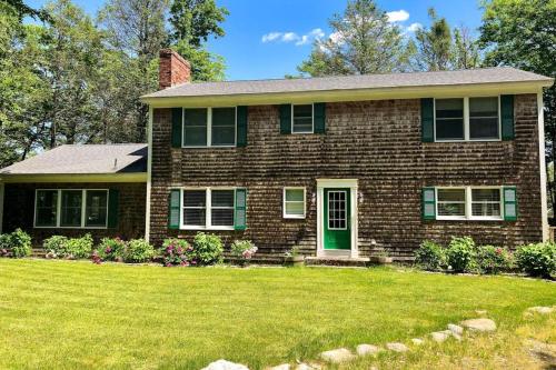 a brick house with a green door and a yard at Tranquil private riverfront home w/ tidal dock & large yard in Boothbay