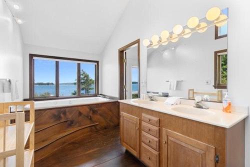 a bathroom with a sink and a large mirror at Clark Point Cottage, ocean access, panoramic views in Clark Island