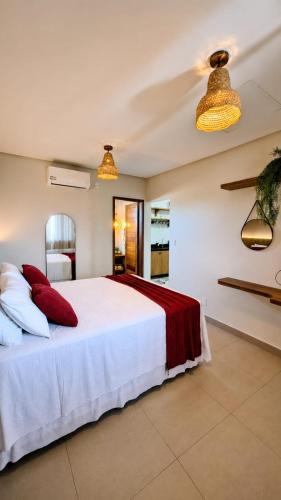a bedroom with a large white bed with red pillows at Pousada Recanto do Luar in Serra de São Bento