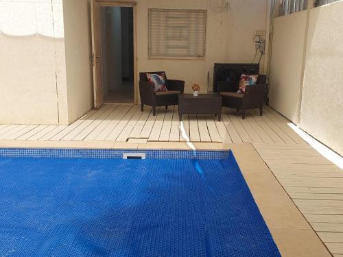 a blue swimming pool in a living room with chairs at וילה אושר in Mitzpe Ramon