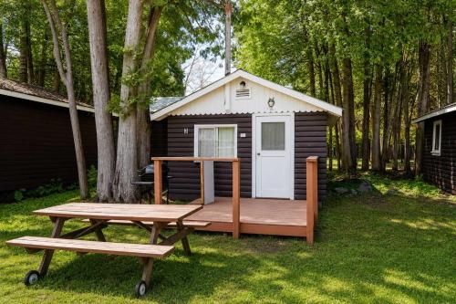a small cabin with a picnic table and a bench at Ambleside - 1-Bedroom Cottage #3 in Kawartha Lakes