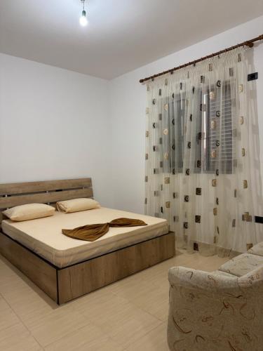 a bedroom with a bed and a curtain and a chair at Garden House - Hamallaj in Hamallë