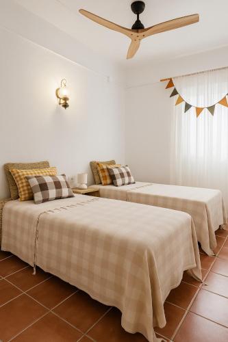 two beds in a room with a ceiling fan at Casa Rural las Tres Rosas in Gaucín