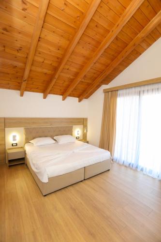 a bedroom with a large white bed and a wooden ceiling at Guesthouse Micaj LUNI in Himare