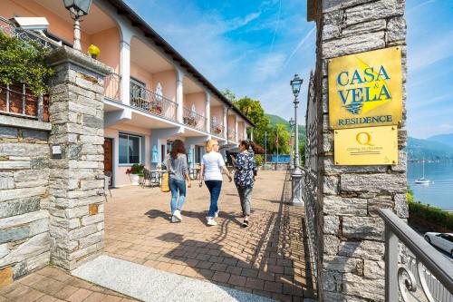 three women walking down a sidewalk next to a building at Residence Casa e Vela in Oggebbio
