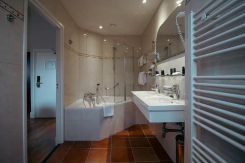 a bathroom with two sinks and a bath tub at Grand Hotel en Résidence De Draak in Bergen op Zoom