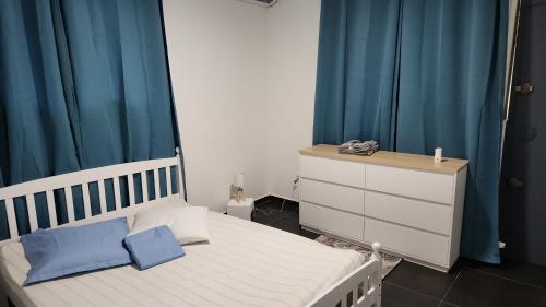 a bedroom with a white bed and blue curtains at Kelinda in Les Abymes