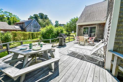 a wooden deck with a picnic table and chairs at Beach Getaway with Private Backyard in Orleans
