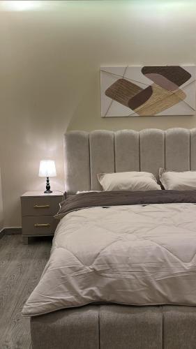 a bedroom with a bed and a table with a lamp at غرفة وصالة دخول ذكي in Al Fayşalīyah