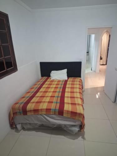 a bed in a white room with a striped blanket at espaço inteiro no bairro mais tranquilo de gravatá in Gravatá