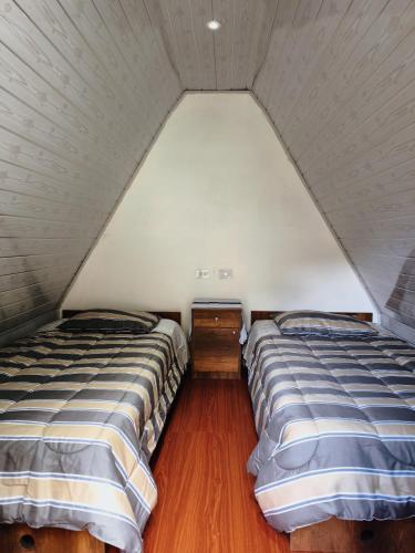 two beds in a room with a attic at EcoSereno Salkantay Huts Chaullay in Santa Teresa