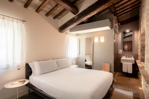 a bedroom with a white bed and a sink at Nun Assisi Relais & Spa Museum in Assisi