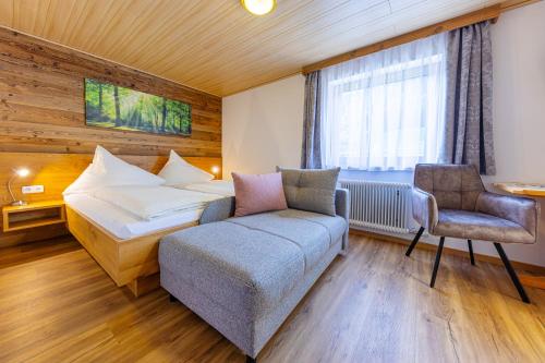 a hotel room with a bed and a chair at Bergbauernhof Familienparadies Oberhasenberghof in Taxenbach