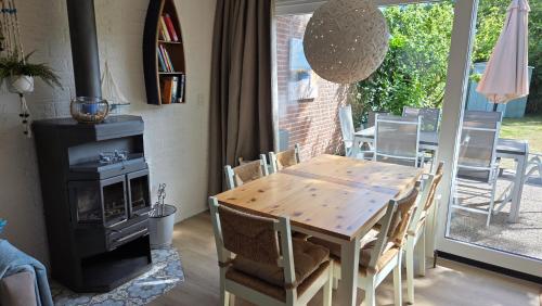 a dining room with a wooden table and a stove at Vakantiehuis Topaz in Bruinisse