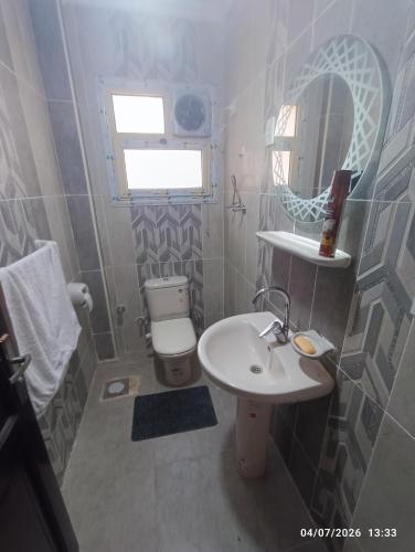 a bathroom with a sink and a toilet and a mirror at عمارة 14 in Madīnat ash Shurūq