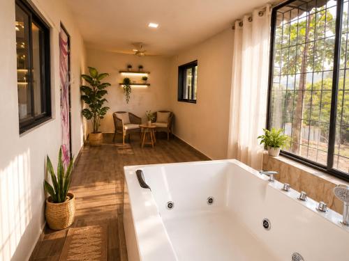 a large white bath tub in a room with a window at Jacuzzi Room in a shared Villa with Swimming pool in Thane