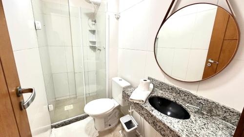 a bathroom with a sink and a mirror and a toilet at Studios Praia Grande - VISTA MAR in Arraial do Cabo