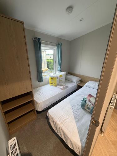 two beds in a small room with a window at The Elms Escape in Porthcawl