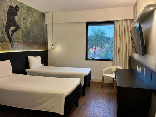 a hotel room with two beds and a television at ibis Styles Taubate in Taubaté