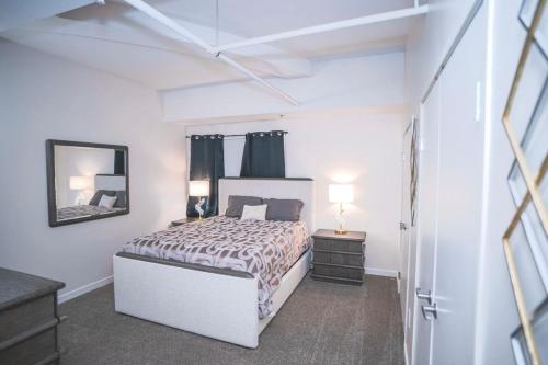 a white bedroom with a bed and a mirror at Urban Escape in Indianapolis