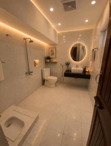 a bathroom with a toilet and a sink and a mirror at Hotel Plaza Park in Nathia Gali