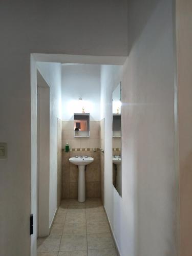 a white bathroom with a sink and a mirror at Duplex EyC in Colón