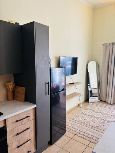 a kitchen with a black refrigerator in a room at Airport Urban Studio in Benoni