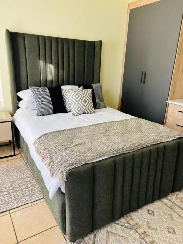 a large bed with a green headboard in a bedroom at Airport Urban Studio in Benoni