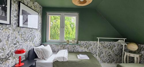 a green room with a bed and a window at Cottage on the Hill in Kielno