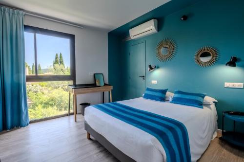 a blue bedroom with a bed and a large window at Hotel Cantosorgue in L'Isle-sur-la-Sorgue