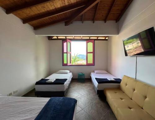 a room with two beds and a couch in it at Aloja-T Hostal Jericó in Jericó